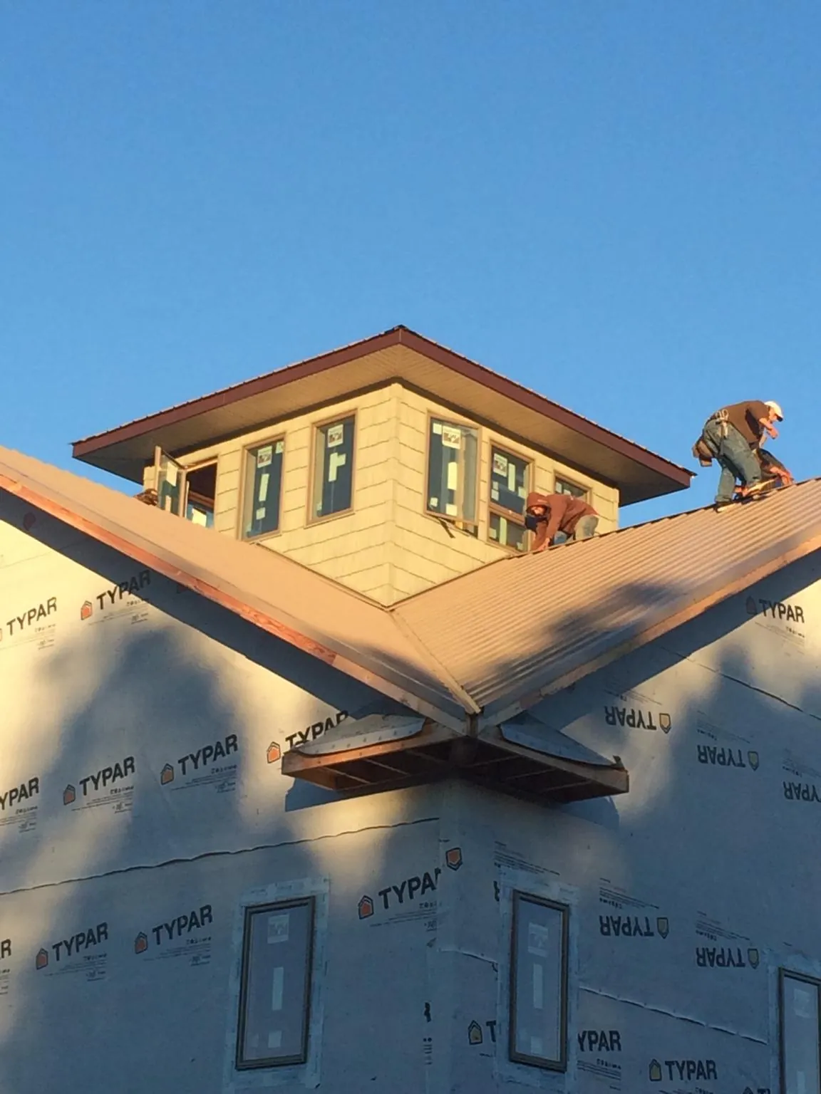 Roofers working around a rooftop cupola on a new metal roof at sunset — Roof Waterproofing in Hemlock by Roofing Brothers